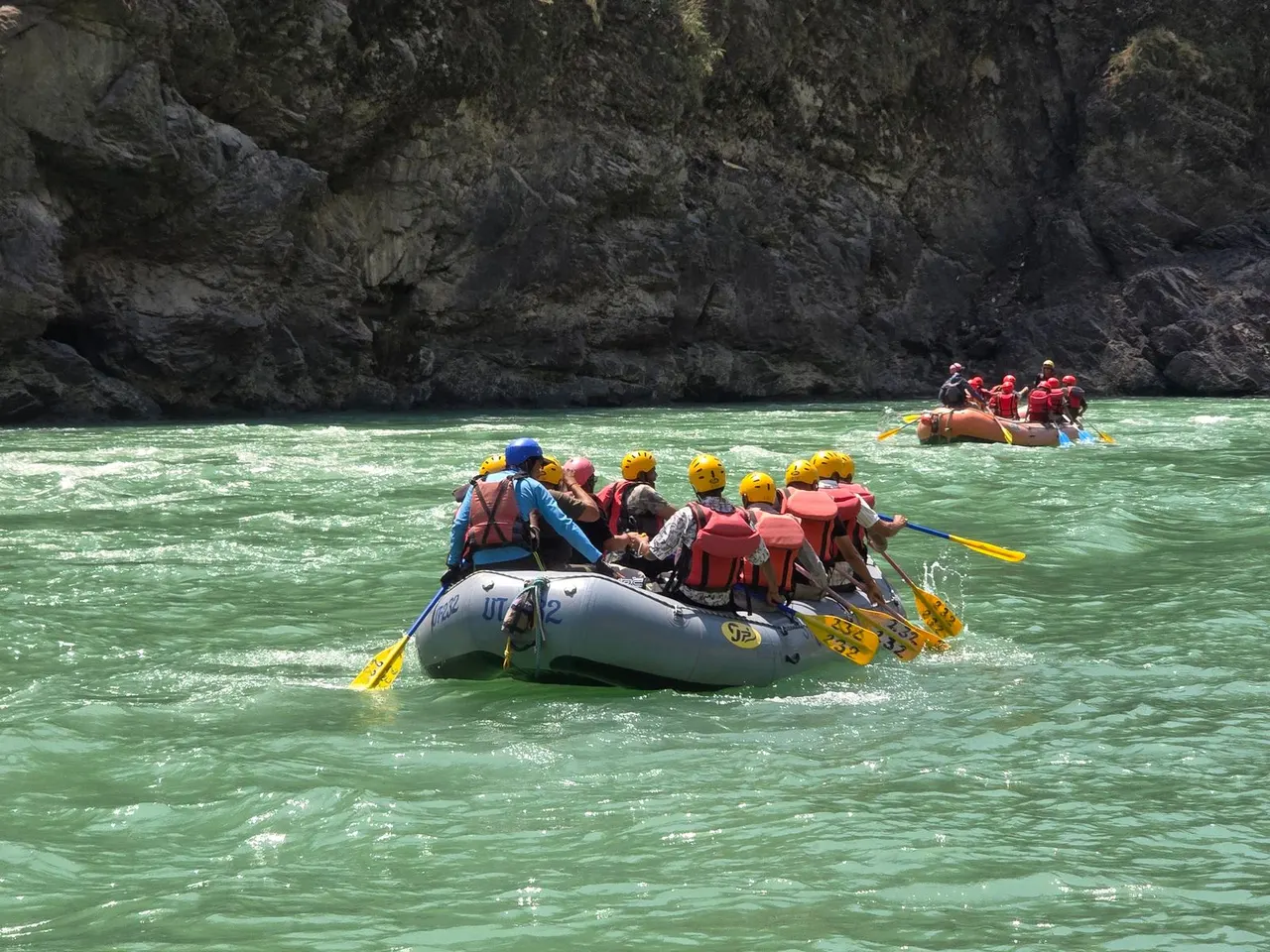 Rafting group paddling between rocky banks on a clear mountain river