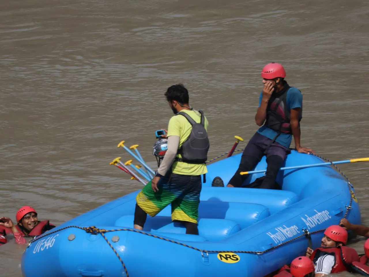 Rafting guide directing a safety drill from a blue inflatable raft