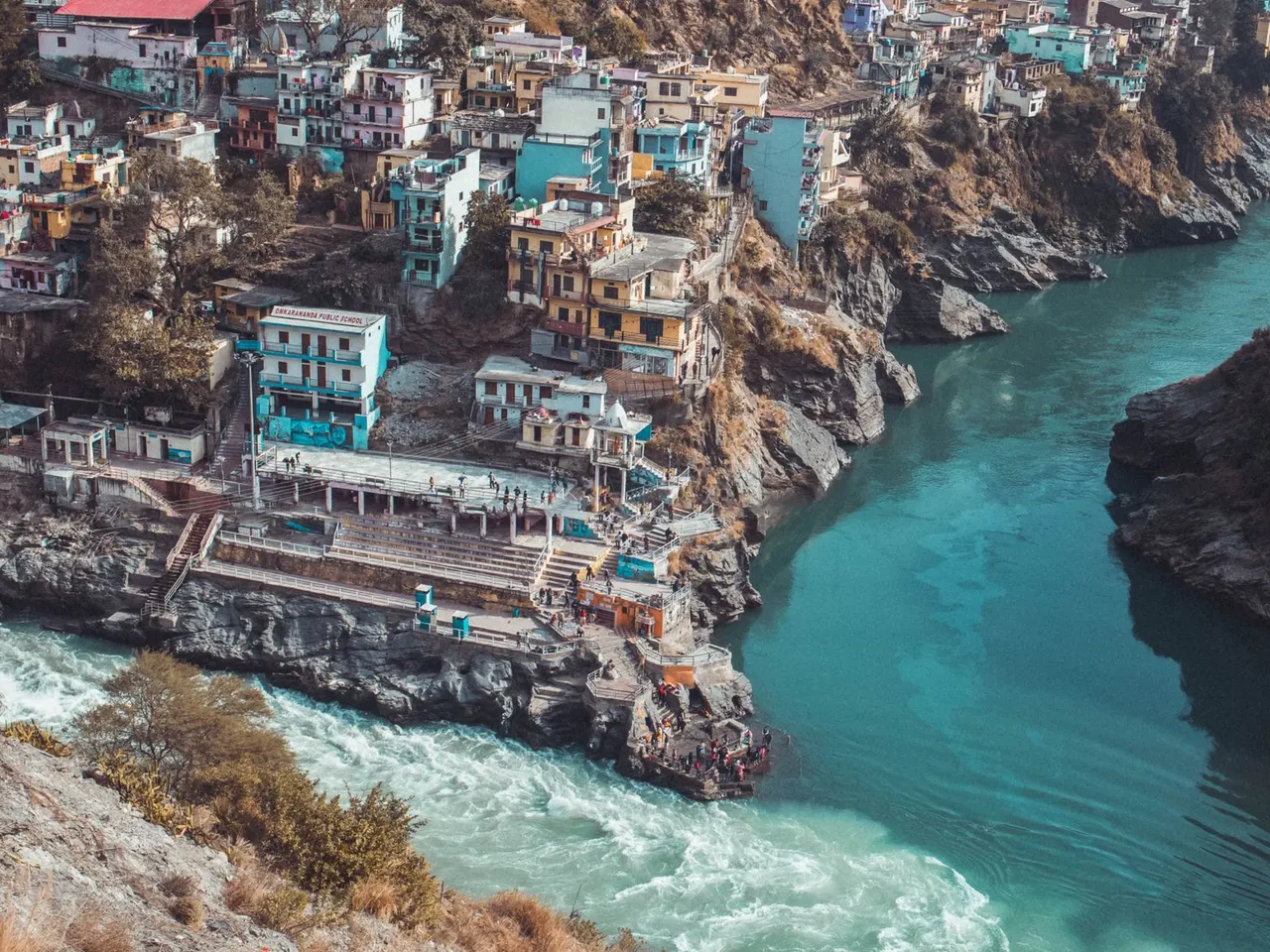 Turquoise river winding past hillside buildings in Rishikesh