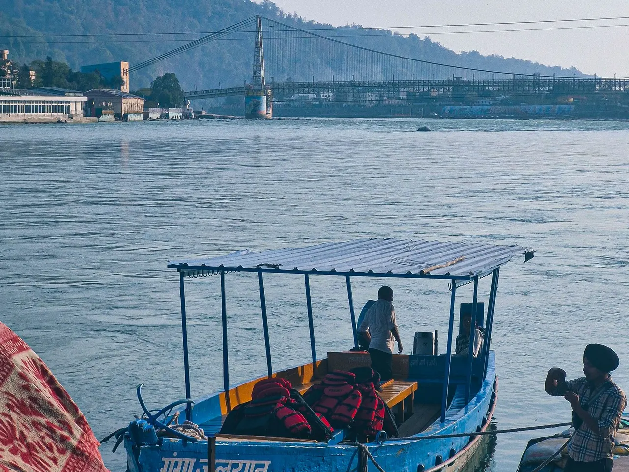 River boat beneath a suspension bridge in Rishikesh