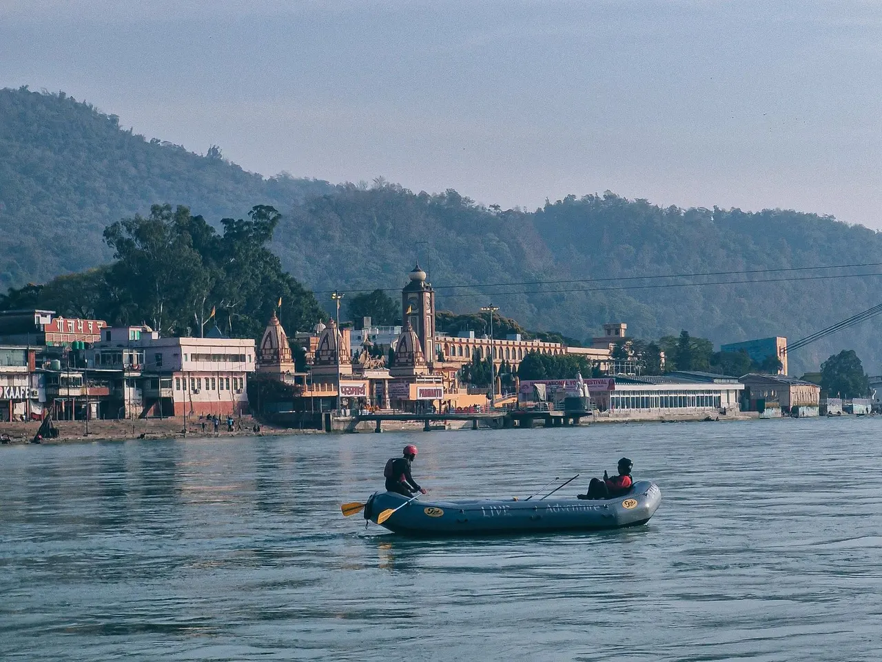 Small rafting boat crossing the river beside the Rishikesh waterfront