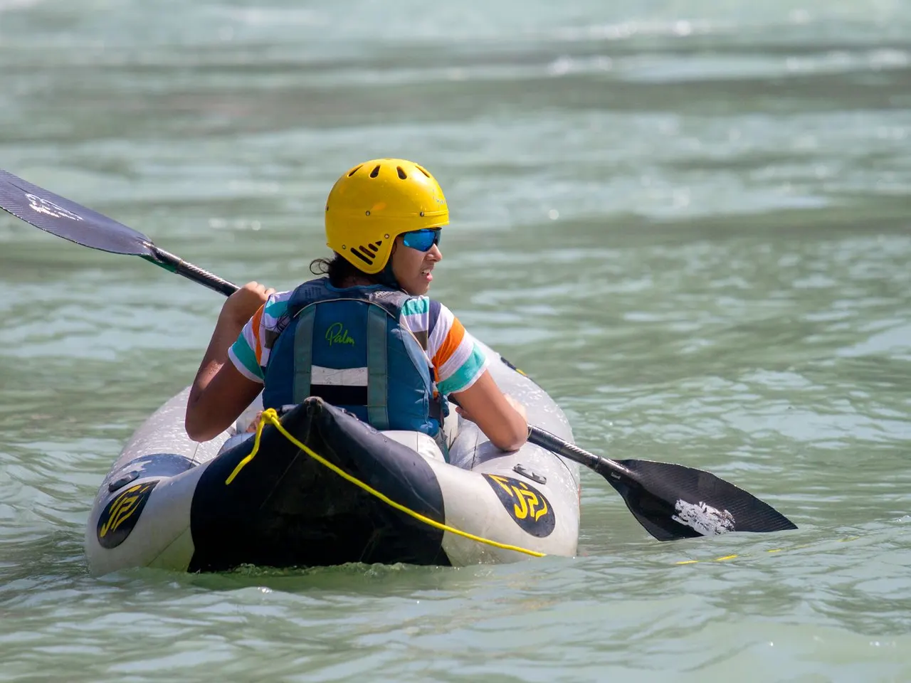 Helmeted safety kayaker paddling through moving river water