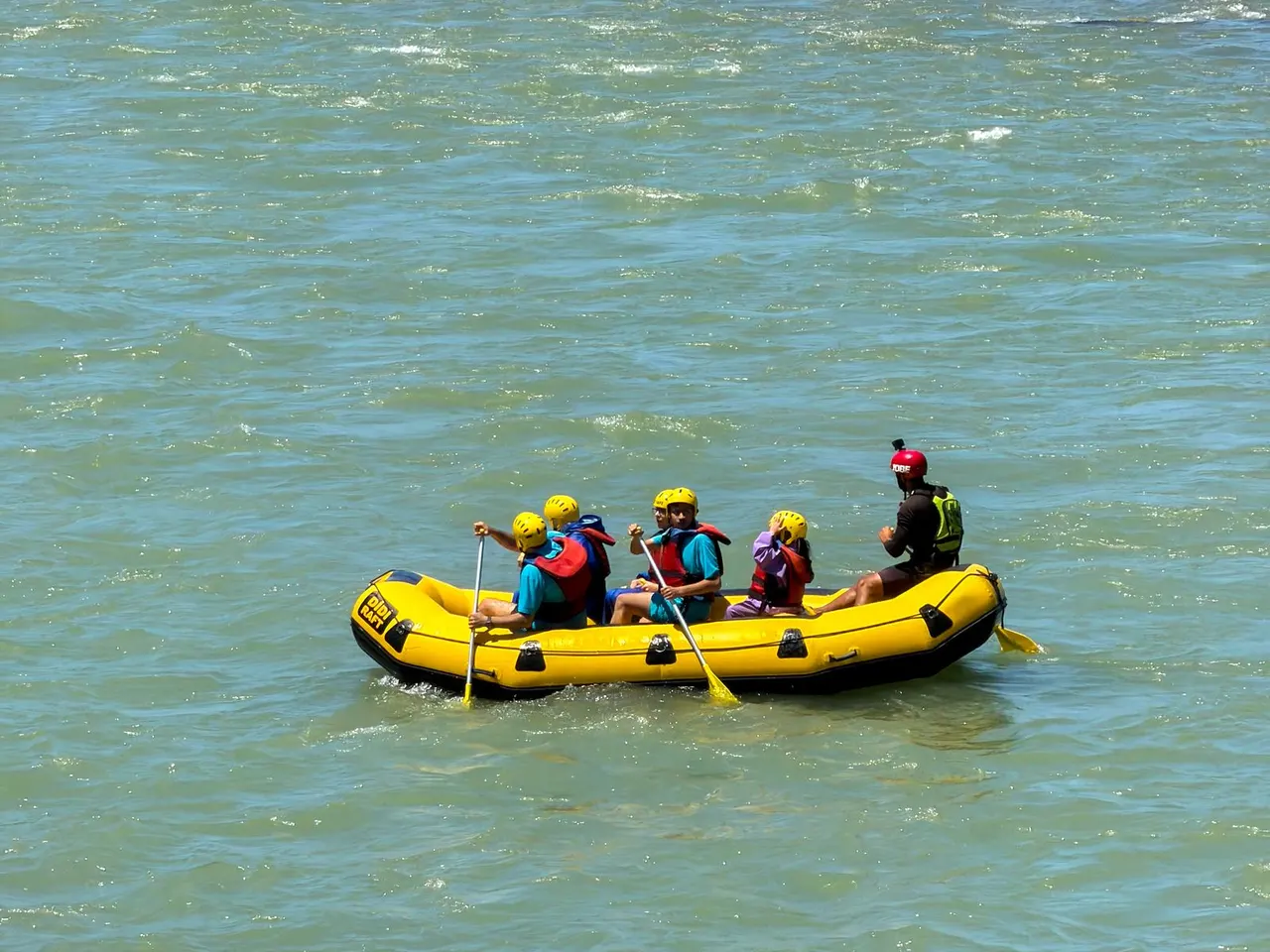 Small rafting group paddling a yellow raft on open river water