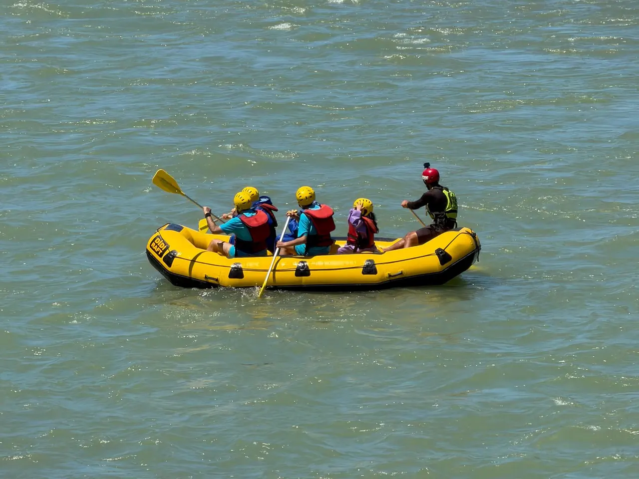 Yellow raft carrying a small group across green river water